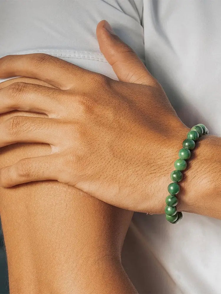 African jade beaded bracelet with smooth green jade beads and gold stainless steel chain worn on a wrist