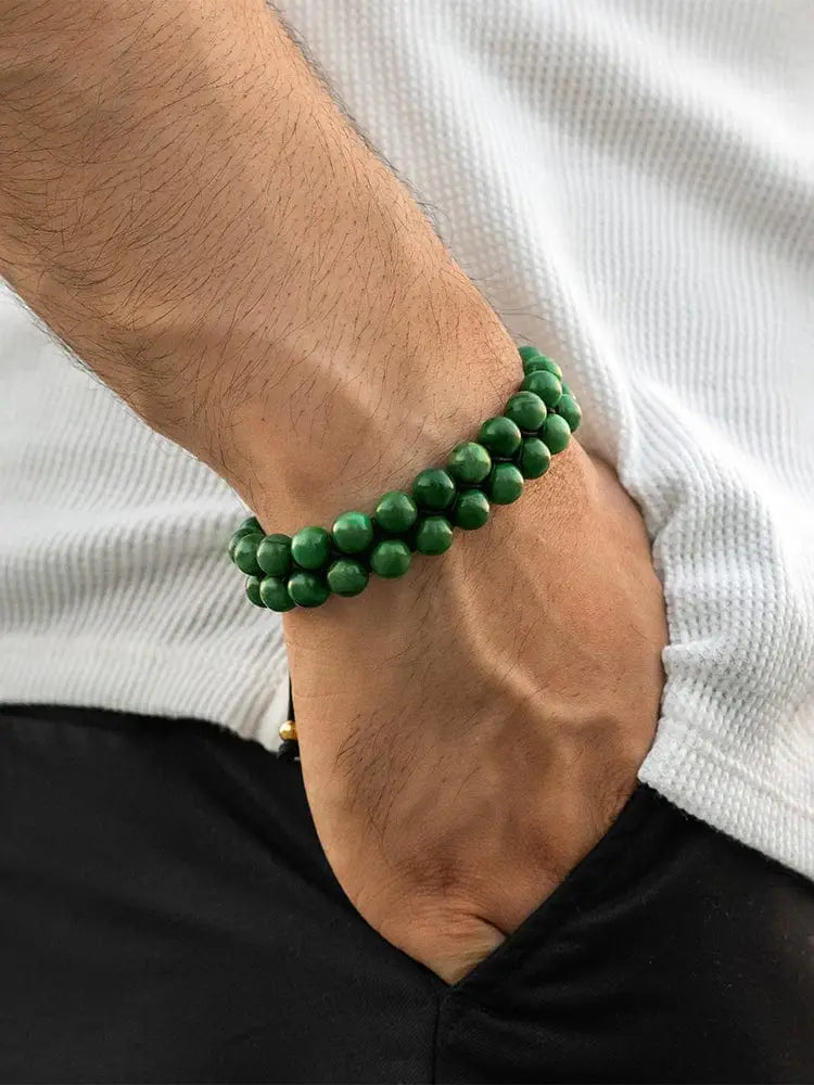 A vibrant green adjustable African jade beaded bracelet with gold accents worn on a wrist