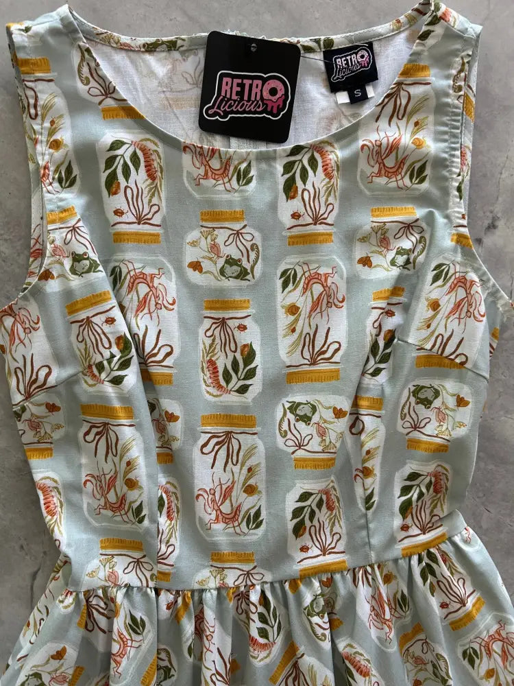 A sleeveless light blue vintage 1950s cotton dress with jars print pattern and pockets by Retro Liquids