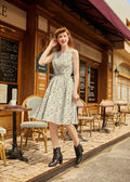 A woman wears a light blue jars print vintage 1950s cotton sleeveless dress with pockets featuring colorful cartoons