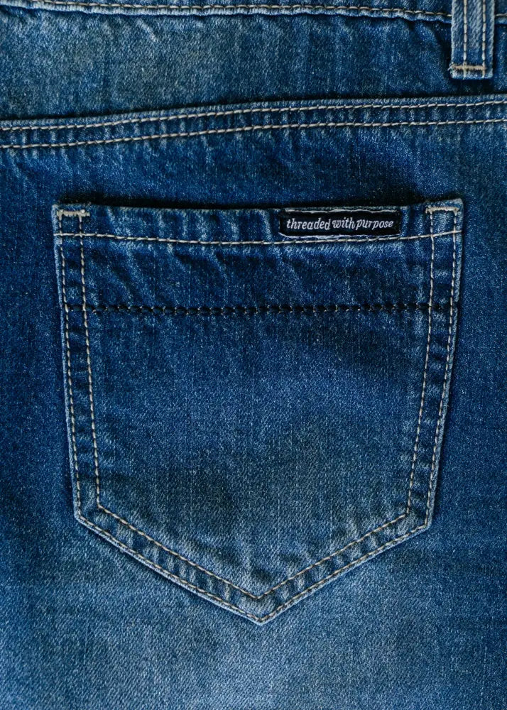 Dark blue denim pocket with white stitching and black threaded with purpose label on back of jennifer premium a-line denim maxi skirt