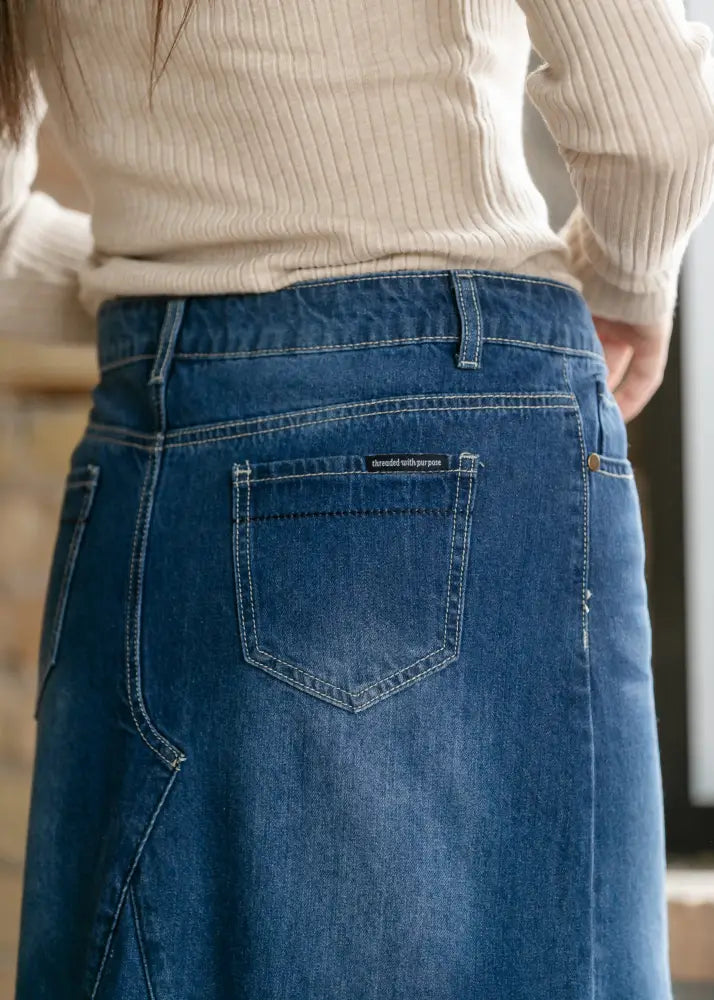 A mid-blue denim jennifer premium a-line maxi skirt with flared hem showing classic back pocket and subtle stitching