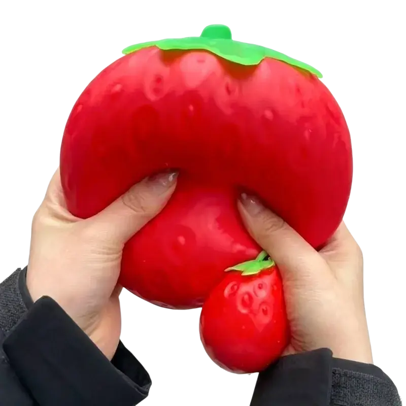 A vibrant red glossy strawberry-shaped jumbo slow rising sensory fidget toy with a green leafy top and textured surface