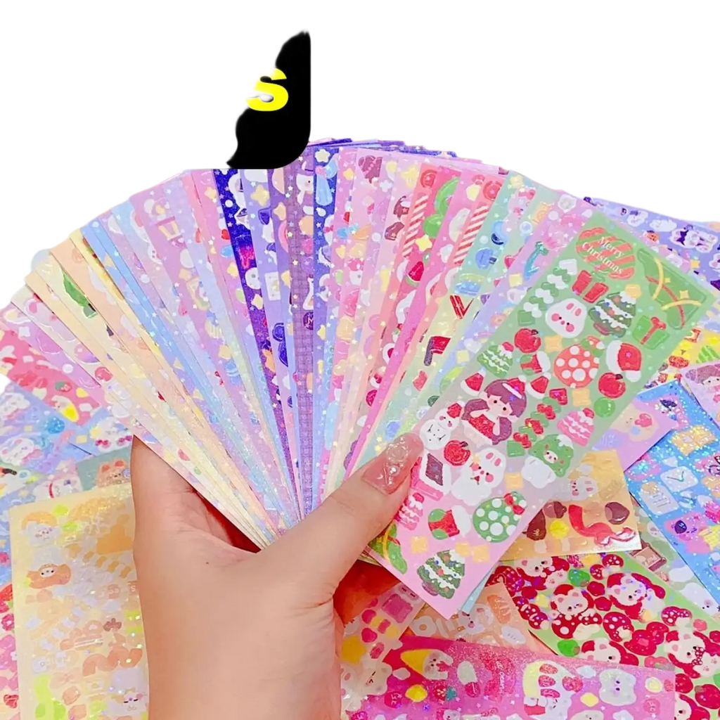 A hand holding colorful glittery kawaii cute cartoon sticker sheets for scrapbooking and diary decor
