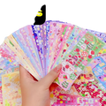 A hand holding colorful glittery kawaii cute cartoon sticker sheets for scrapbooking and diary decor