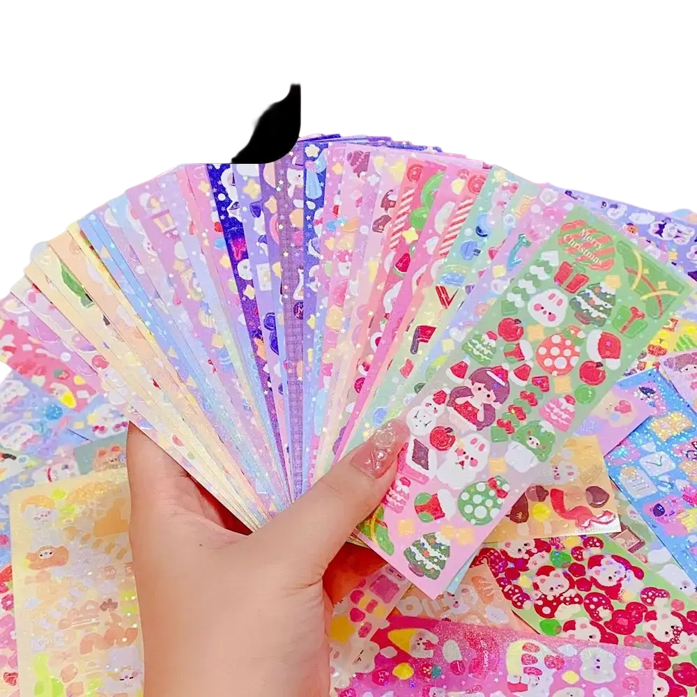 A hand holding colorful glossy kawaii cute cartoon sticker sheets for scrapbooking and diary decor