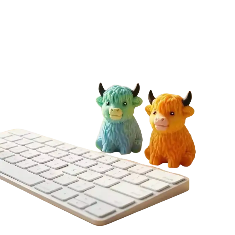 Two colorful textured kawaii highland cow squishy stress relief toys displayed side by side on a desk