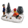 Kids playing snow Christmas village figurine set with colorful children building snowman among frosted pine trees