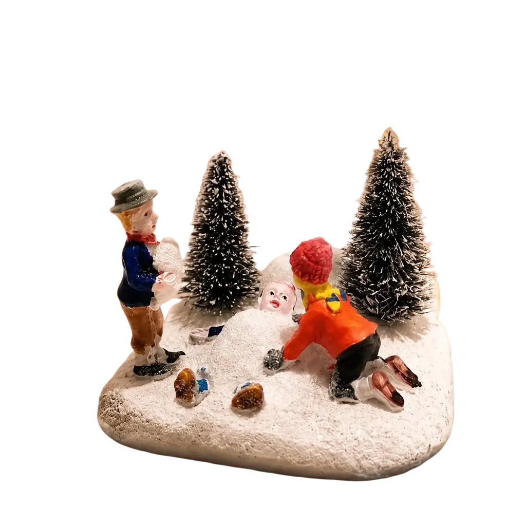 Kids playing snow christmas village figurine set with two children building a snowman on a snowy base with trees and houses