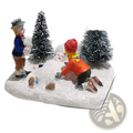 Kids playing snow Christmas village figurine set with colorful children building snowman among frosted pine trees