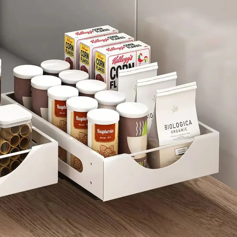 Adjustable white plastic kitchen drawer dividers with multiple compartments organizing cereal, jars, and coffee bags
