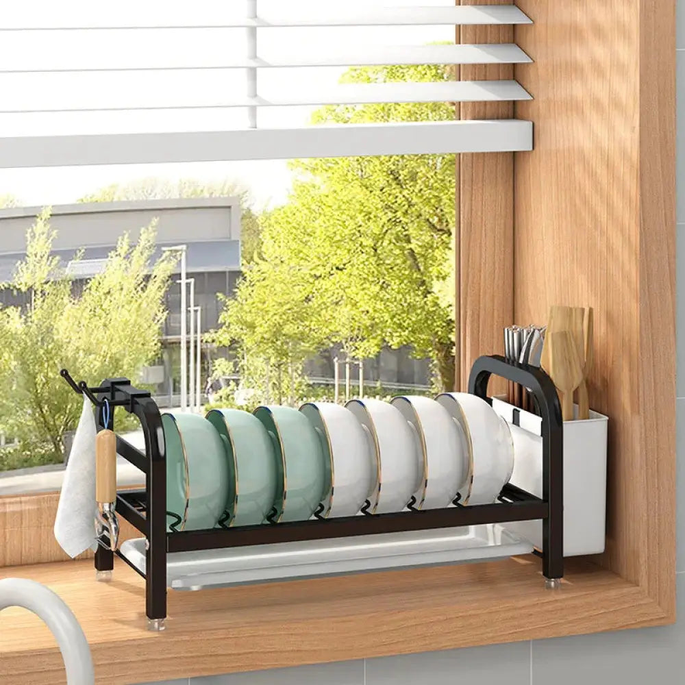 Two tier black metal kitchen dish drying rack with white utensil container and hanging towel hook for organization
