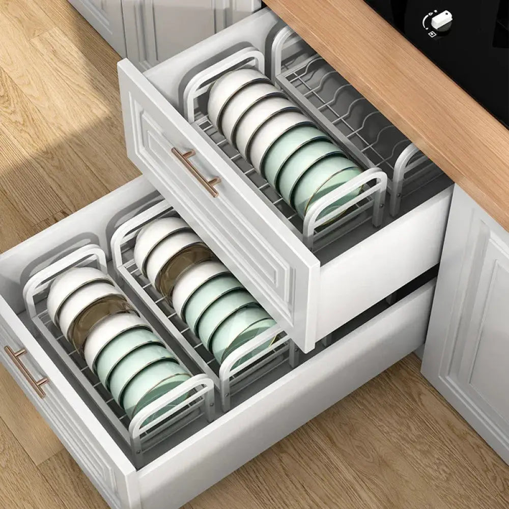 Two tier metal kitchen dish drying rack and organizer with white and mint green ceramic plates in an open drawer