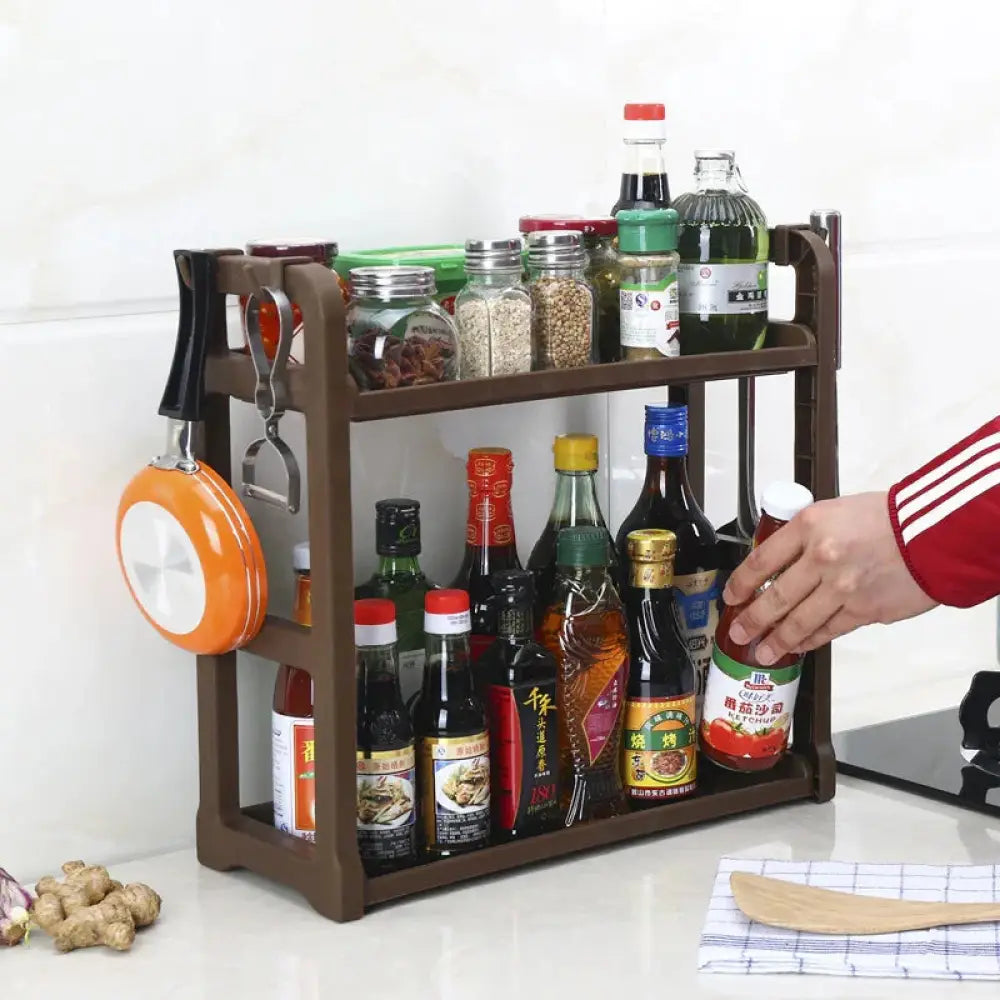 Brown plastic multilayer two tier kitchen spice and utensil organizer rack with hooks holding frying pan and utensils