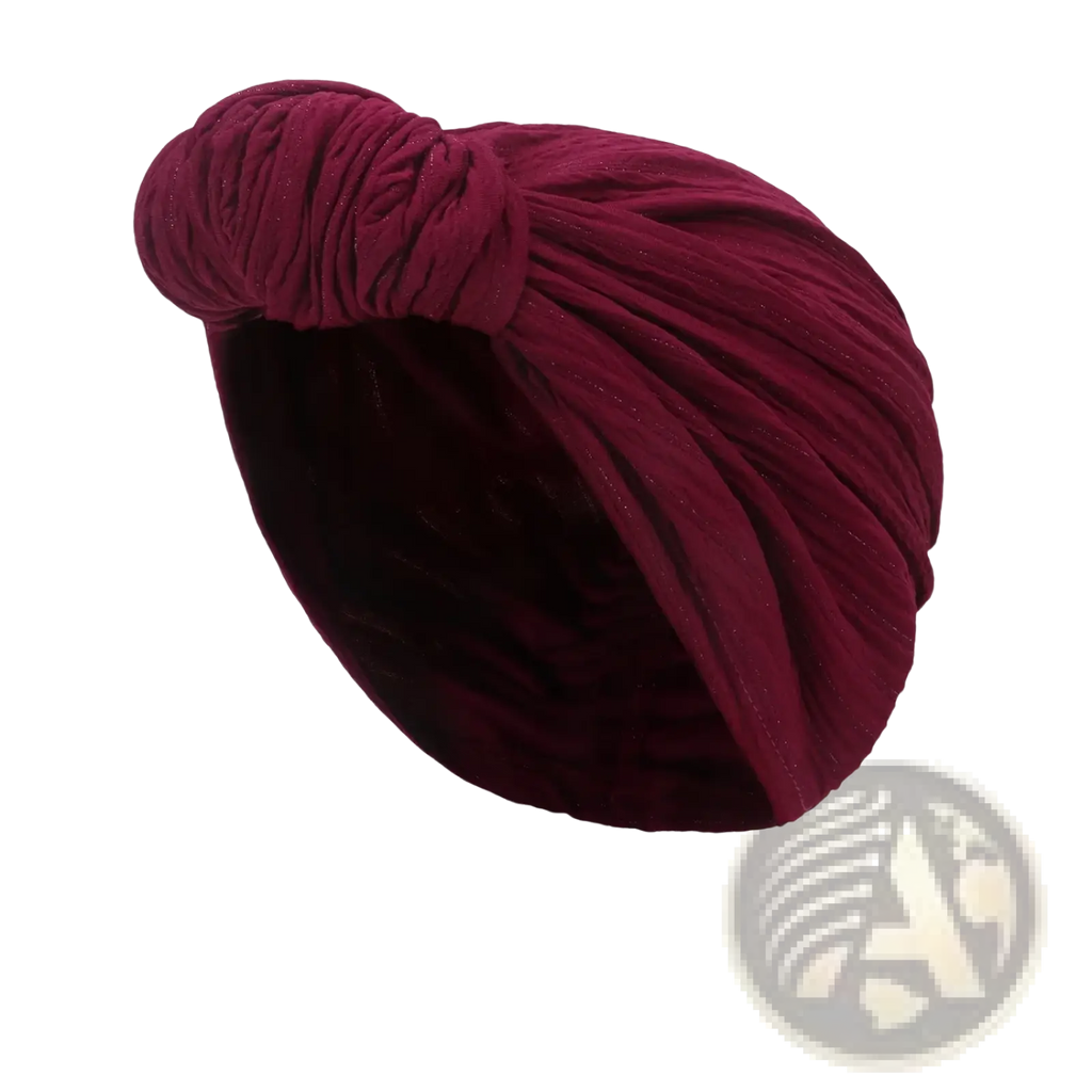 A plush deep rose velvet knitted turban cap with a twisted knot design for warm winter headwear