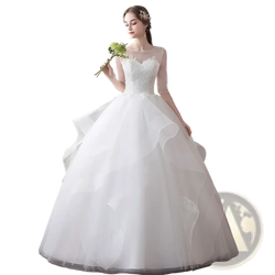 A white lace ball gown wedding dress with sheer long sleeves and a voluminous tulle skirt plus size