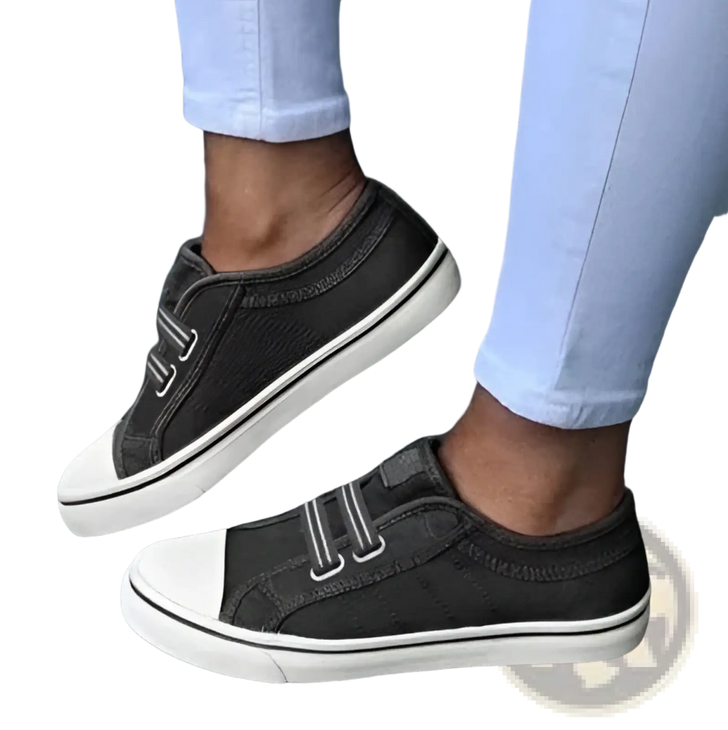 Black laceless canvas sneakers with white rubber soles and two velcro straps for easy slip on wear