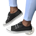 Black laceless canvas sneakers with white rubber soles and two velcro straps for easy slip on wear