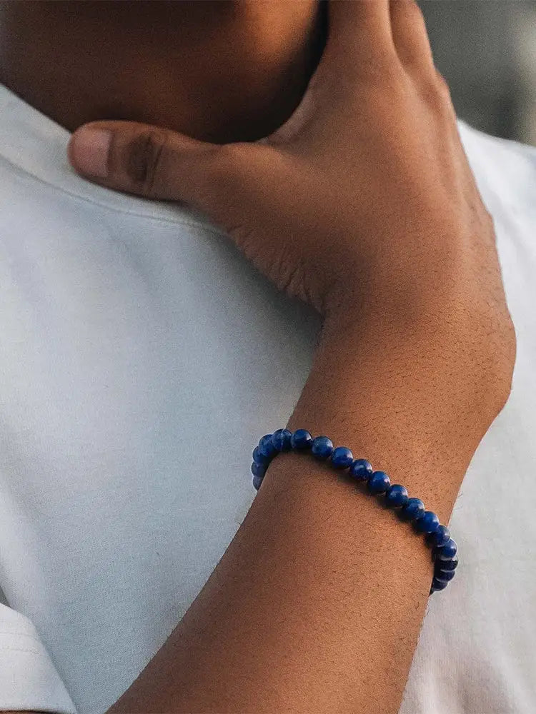 Aaa lapis lazuli beaded bracelet with deep blue round beads and silver greek key chain worn on a wrist