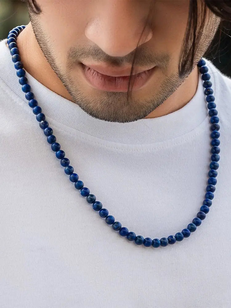 A deep blue lapis lazuli bead necklace with silver accents worn around the neck for elegant use