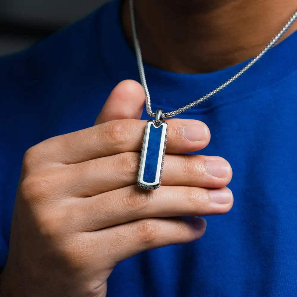 Silver-toned stainless steel dog tag necklace with vibrant lapis lazuli blue inlay and engraved border on matching chain