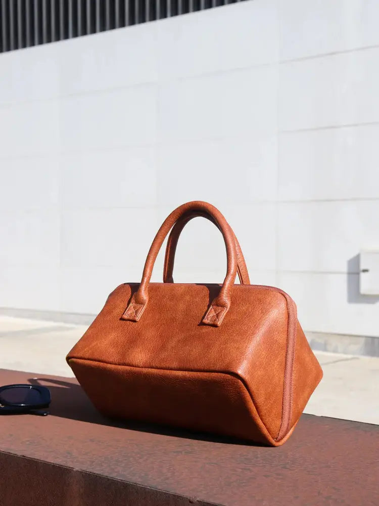 A large tan pu leather travel makeup and toiletry organizer satchel with a structured shape and top handles