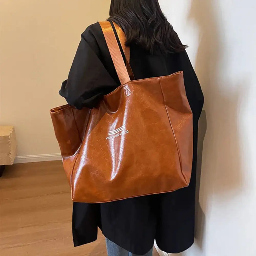 Brown faux leather large waterproof glossy shoulder tote bag with subtle embossed logo on the front