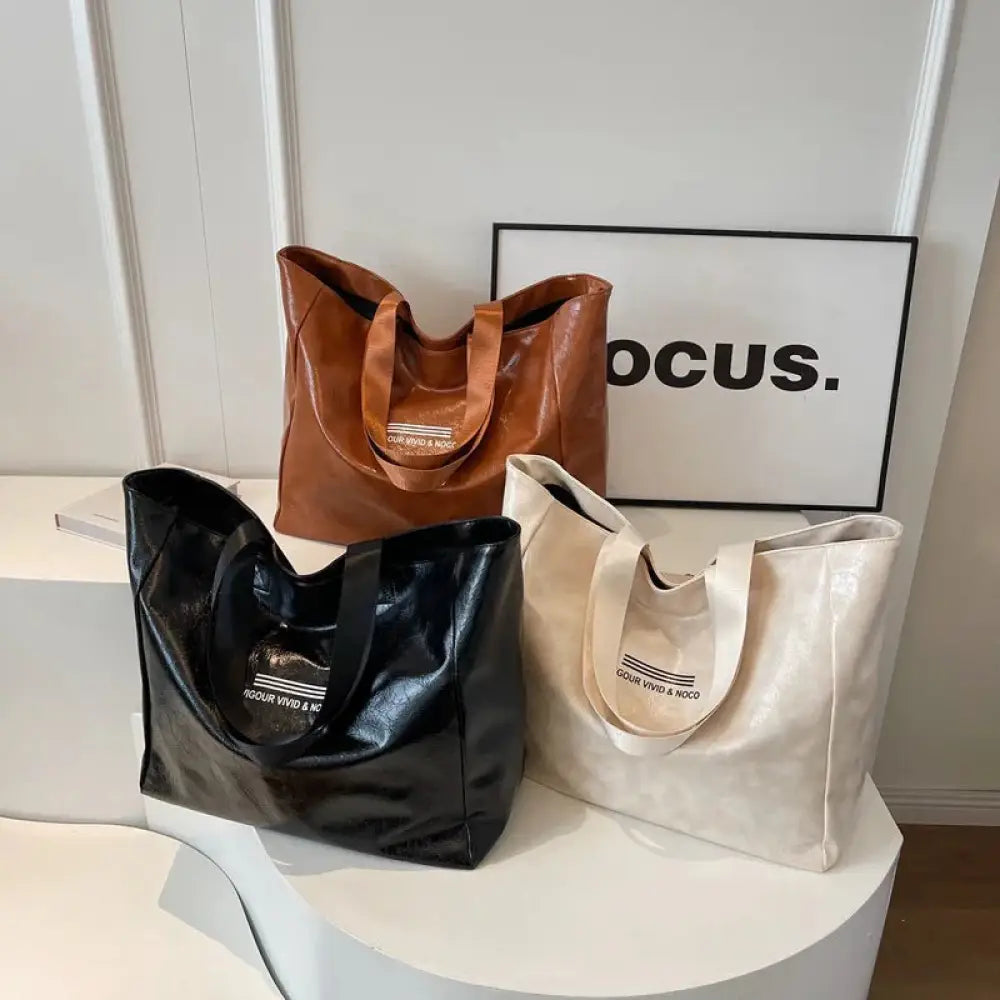 Large waterproof glossy shoulder tote bags in brown black and cream with matching handles and a shiny finish