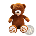 A large plush teddy bear soft velvet 1 meter in brown with white paw pads and stitched nose sitting on wooden floor