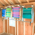 Stud mounted steel lawn chair storage hooks holding four colorful striped metal frame beach chairs on wall rack