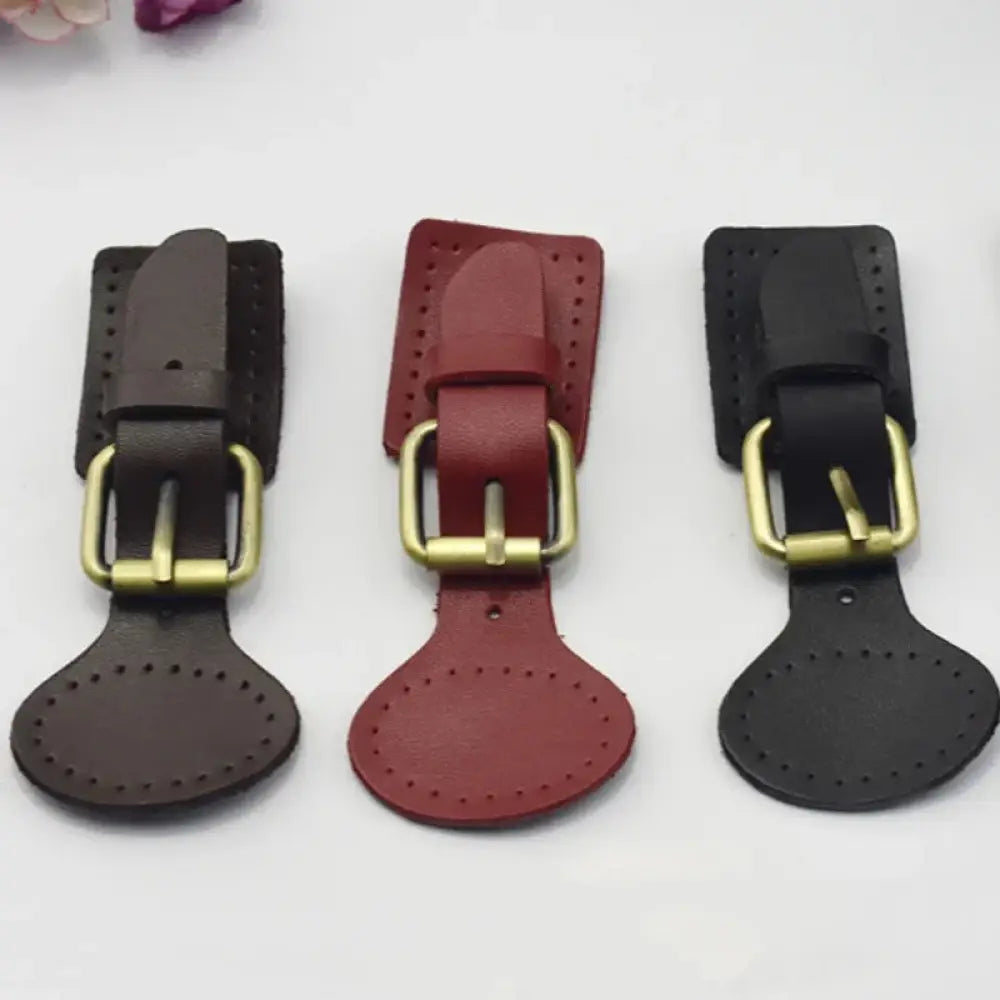 Three handcrafted oval leather hook fasteners in brown red and black with brass hardware and metal buckles