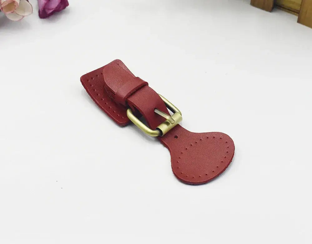 Handcrafted oval red leather hook fastener with brass hardware decorative stitching and toggle buckle