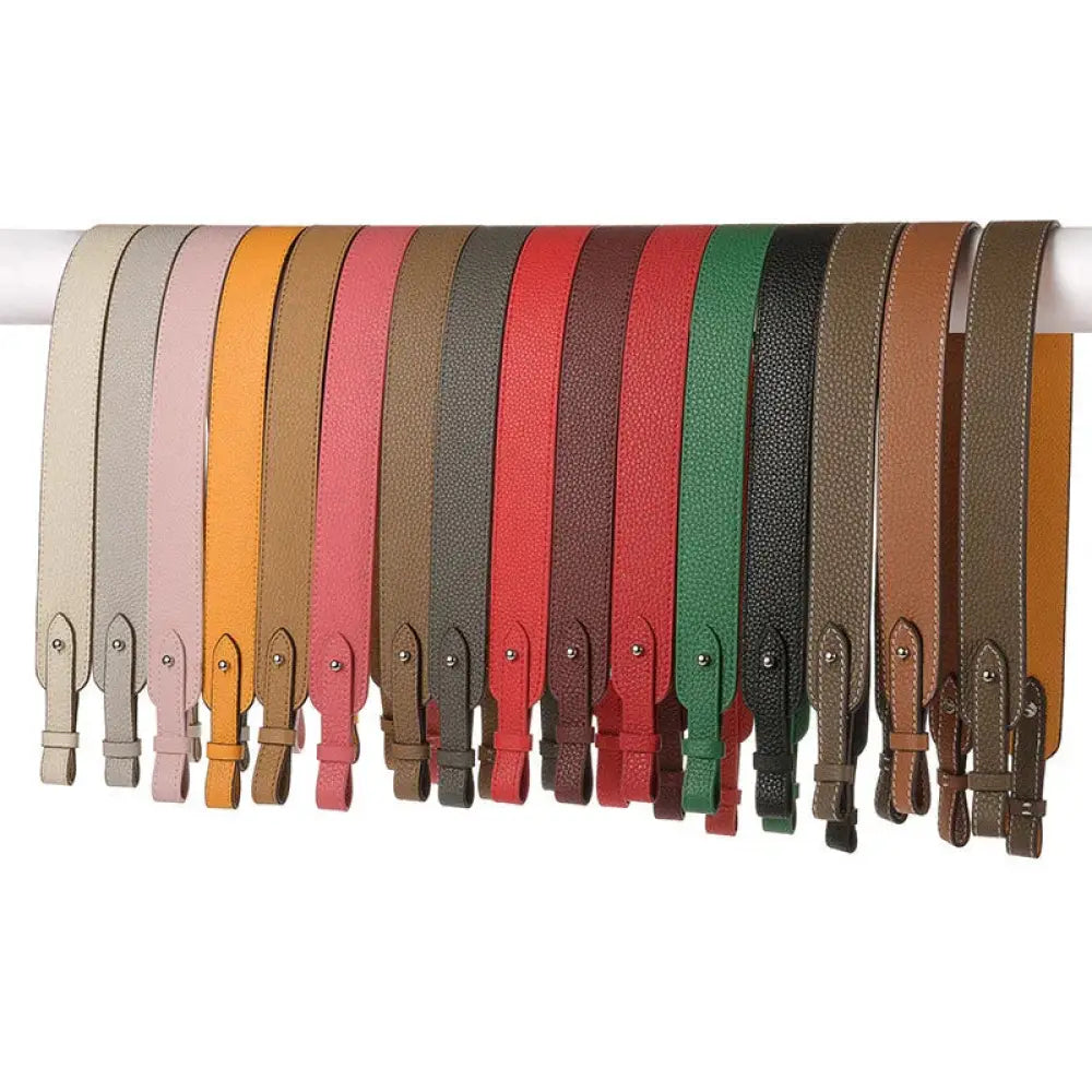 A collection of adjustable textured leather handbag straps in beige pink orange red green and black with gold clasps