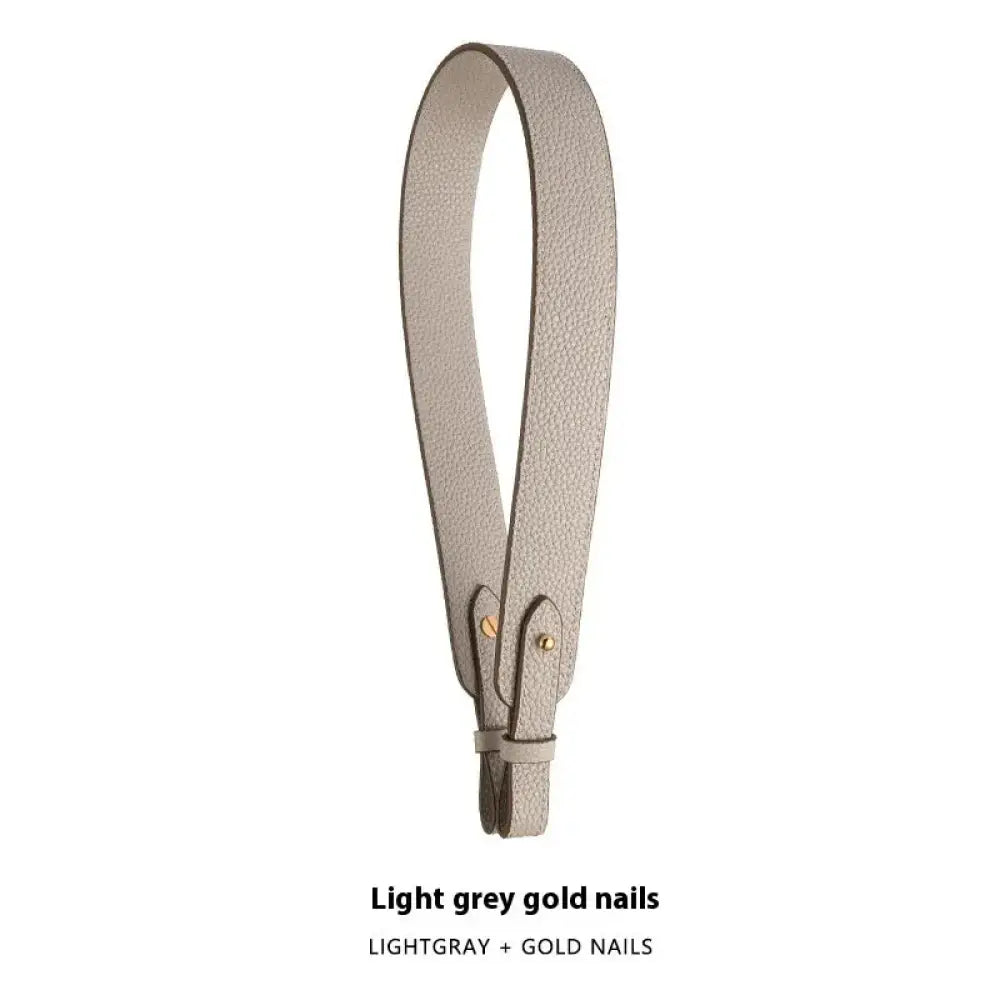 Adjustable textured leather handbag strap in light grey with gold-colored metal nails and gold clasp