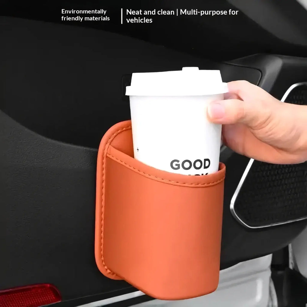 Orange leather car seat organizer and cup holder holding a white coffee cup in the car interior