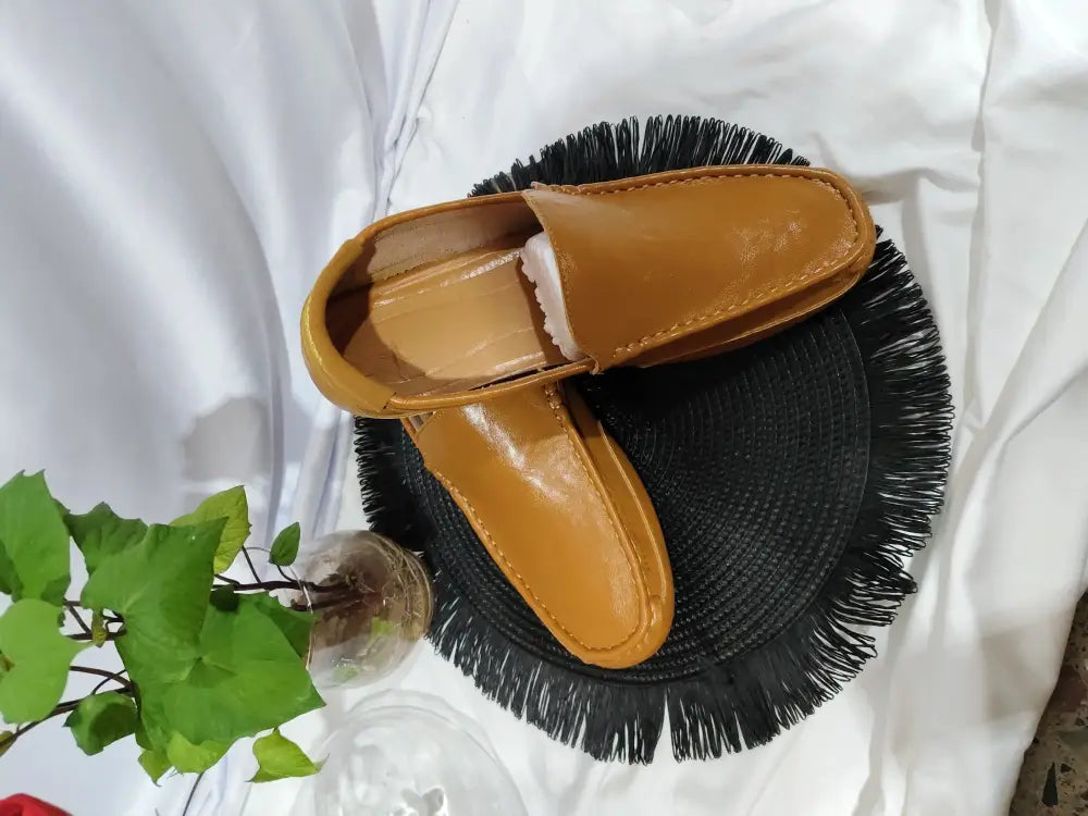 Men’s soft leather slip on loafers in tan with a smooth glossy finish and visible stitching along the edges