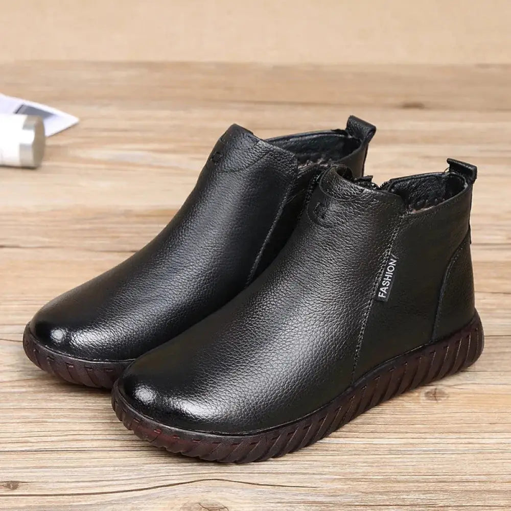Women’s non-slip black leather ankle boots with textured surface and dark brown rubber soles for warmth and comfort