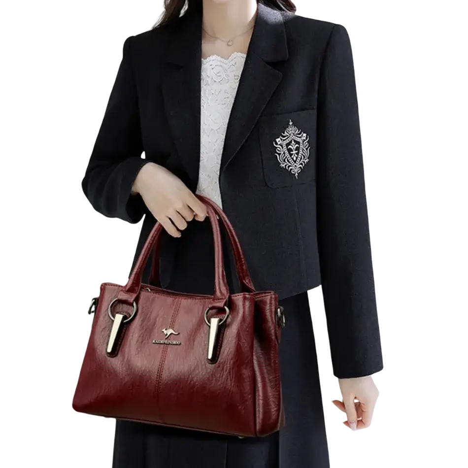 Burgundy leather crossbody handbag with silver hardware, kangaroo logo plaque, and a pocket interior for organization