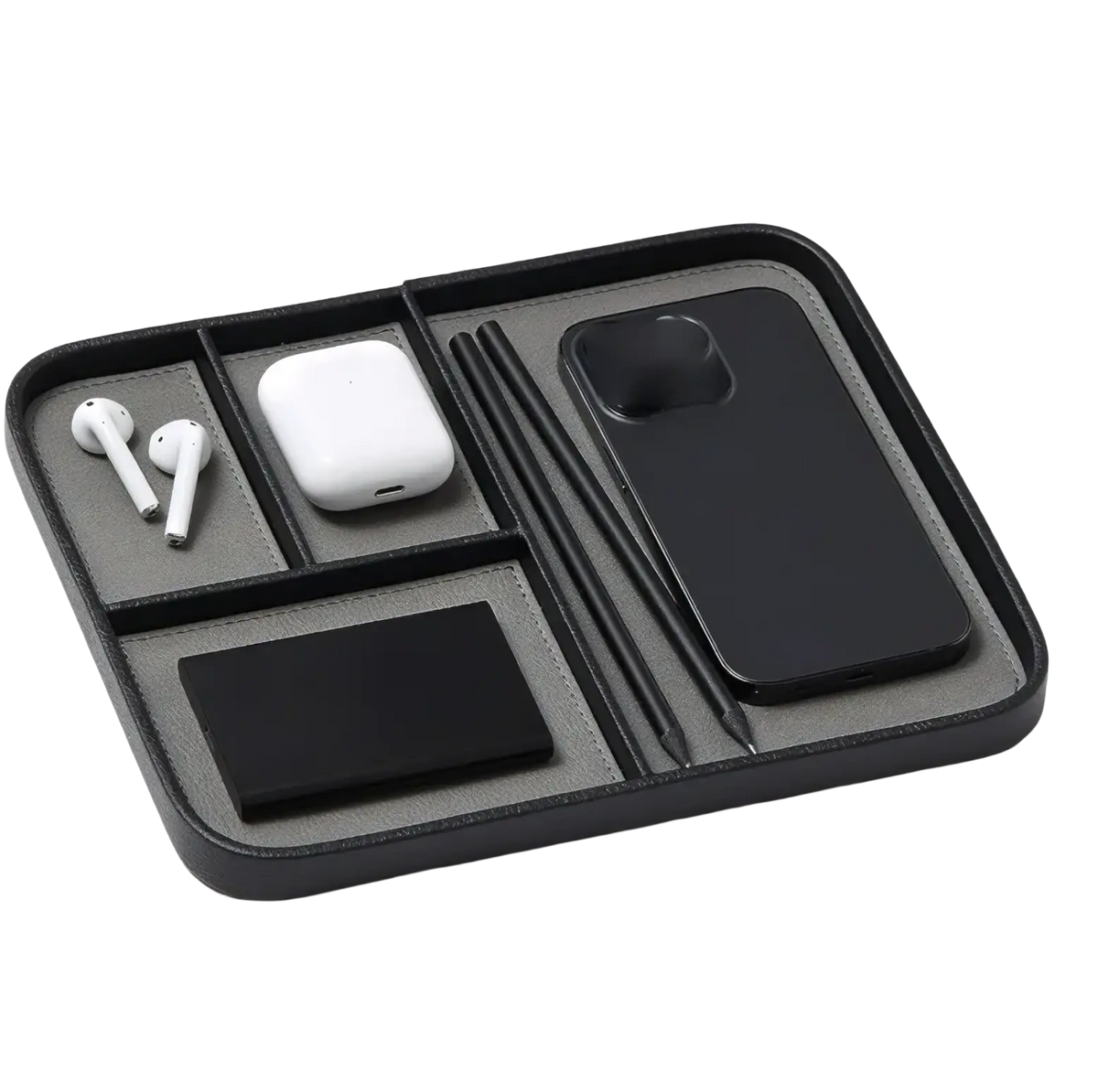 Black leather desktop organizer tray with segmented compartments holding wireless earbuds phone case and stylus pens