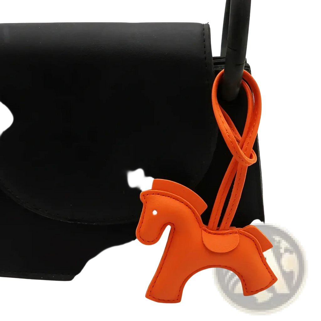 Orange leather horse bag charm keychain with a looped strap attached to a black bag handle