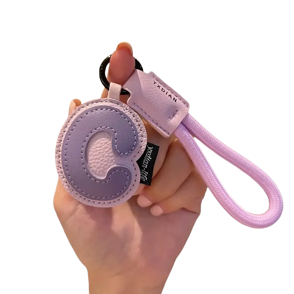 Lavender leather initial keychain with circular letter c design, contrasting stitching, and braided wristband charm