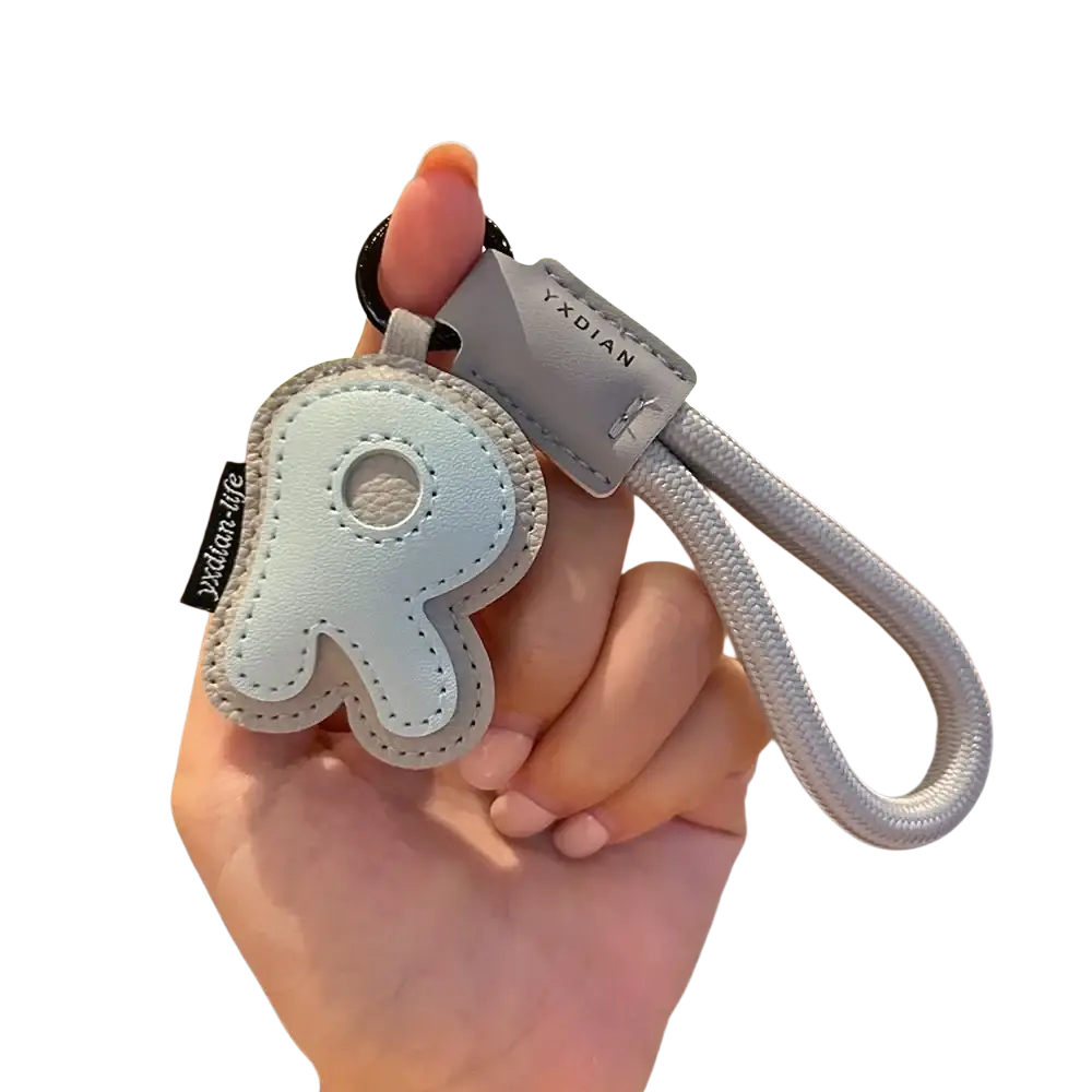 A light blue leather initial keychain shaped like the letter r with gray fabric loop and stitched edges