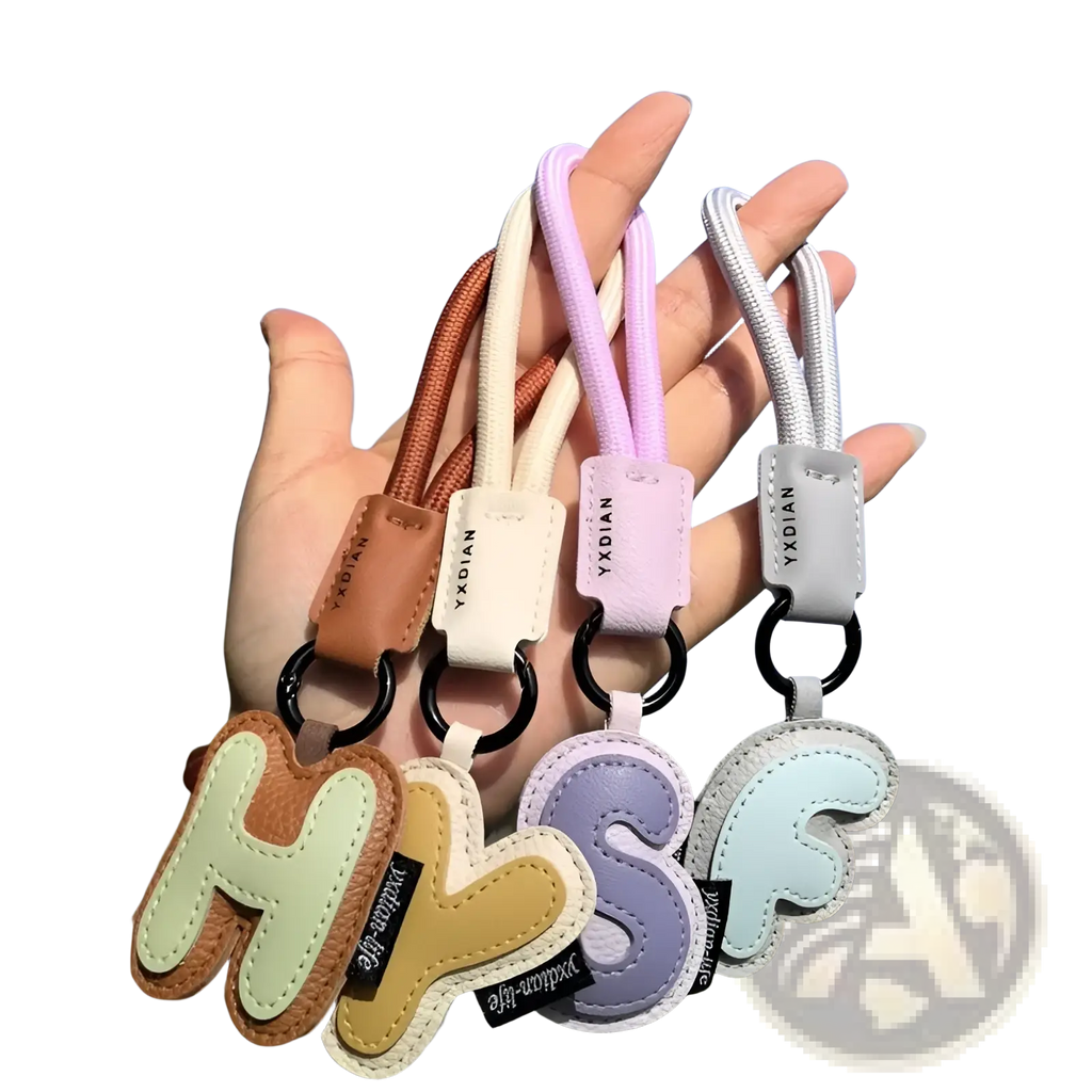 Pastel-colored leather initial keychain letter wristband charm with contrasting stitching and black metal rings