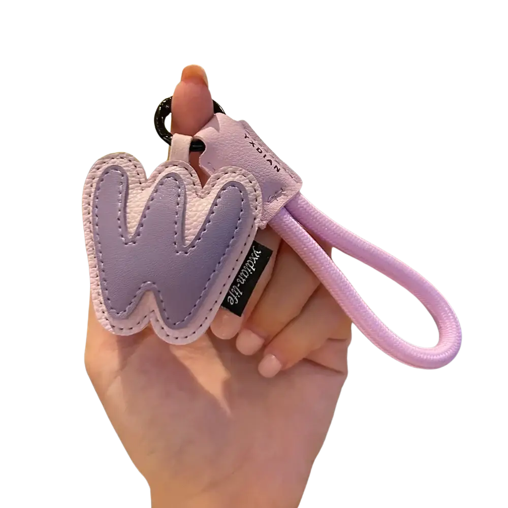 A soft lavender leather initial keychain heart charm with white w stitching, pink fabric loop, and black metal ring