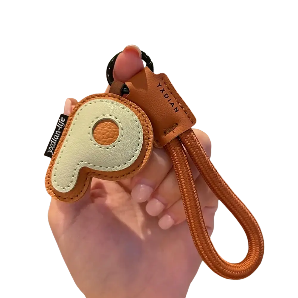Leather initial keychain letter wristband charm in tan and cream leather shaped like letter p with braided orange strap