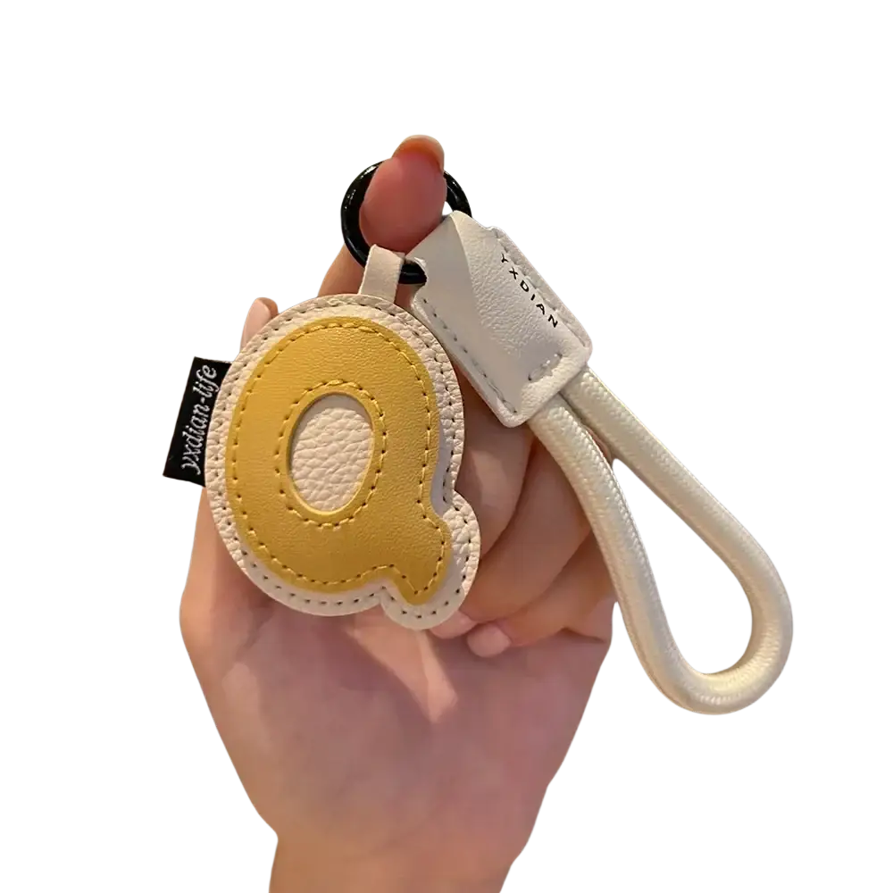 Yellow leather initial keychain letter q with white stitching and matching strap for wristband charm use