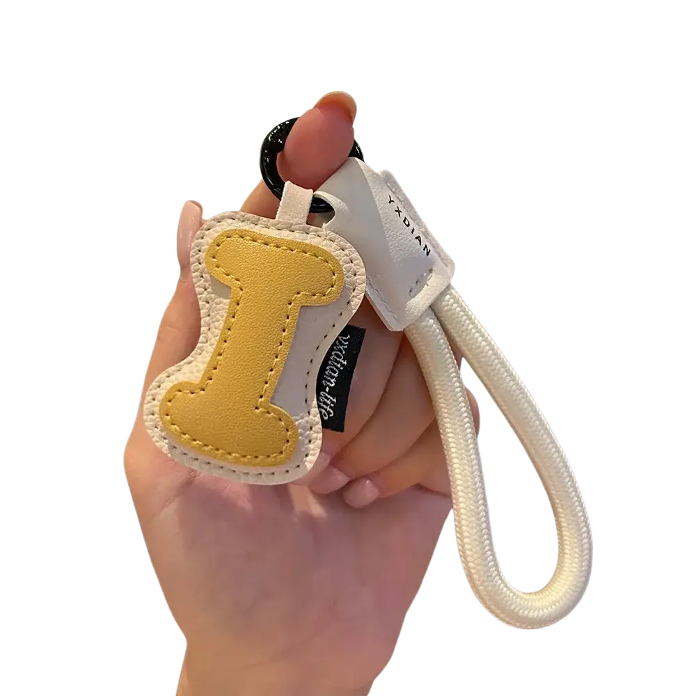 Yellow leather initial keychain letter i with white stitched edges and braided strap for wristband charm use