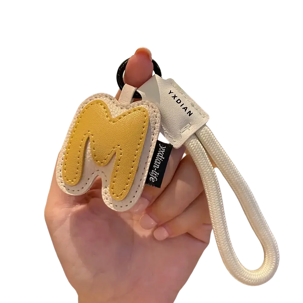 Leather initial keychain letter wristband charm featuring a yellow and cream leather letter m with white braided strap