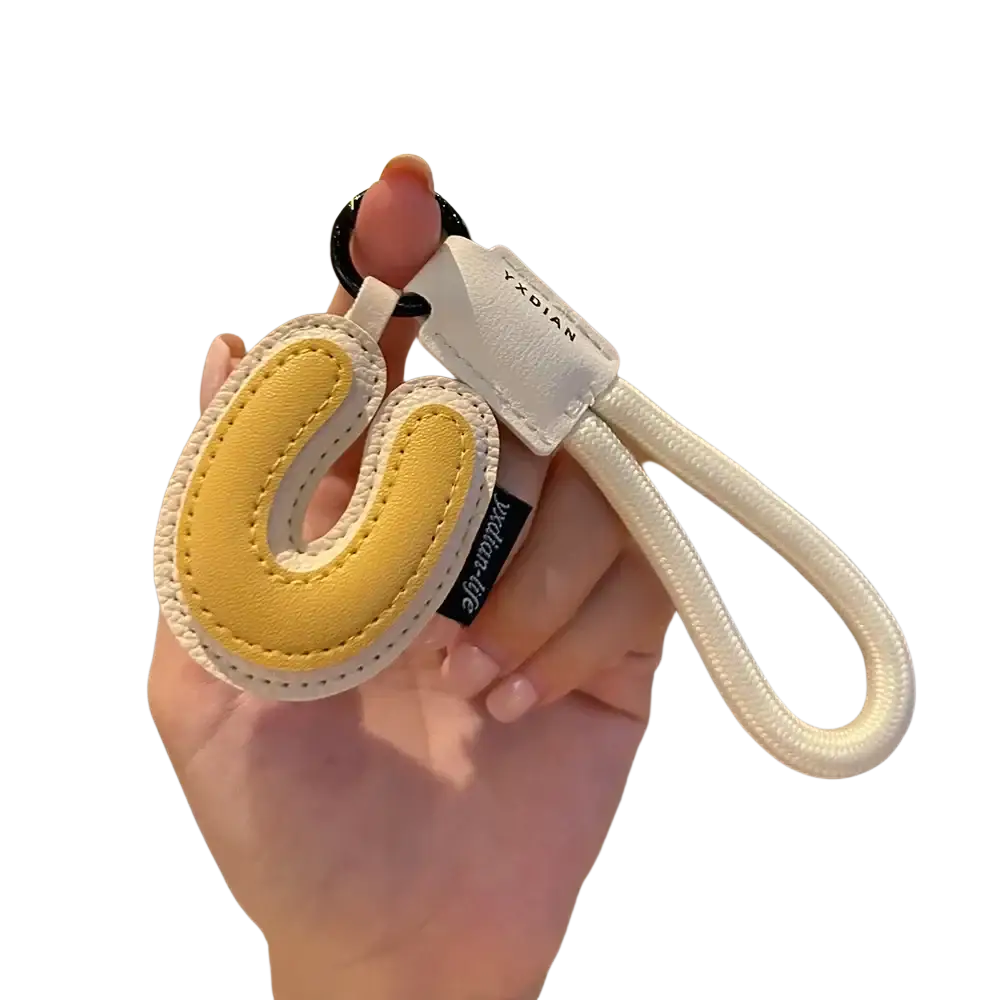 Yellow and white leather initial keychain shaped like letter u with braided strap for wristband charm use