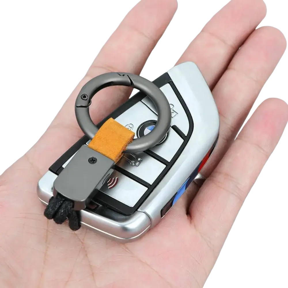 Silver bmw key fob attached to a leather keychain lanyard with a matte black metal ring carabiner and orange strap
